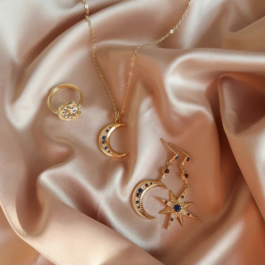 Ensemble de bijoux dorés pour femme avec pendentif croissant de lune et étoiles bleues sur tissu satiné, idée cadeau femme.